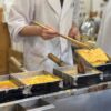 A person in a kitchen preparing food with chopsticks