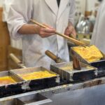 A person in a kitchen preparing food with chopsticks