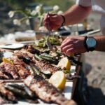 a person holding a fork over a table of seafood