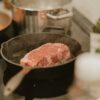 A pan with some meat in it on a stove
