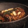 cooked meat with green vegetable on black ceramic plate