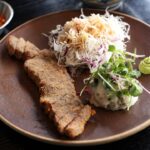 A plate of grilled meat with salad and kimchi.