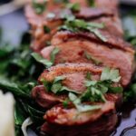 grilled meat with green vegetable on white ceramic plate