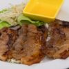Grilled pork chops with a side of lettuce and sauce.