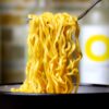 a close up of a bowl of noodles with a fork in it