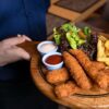 fried food with green vegetable on brown wooden round plate