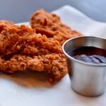 a plate of fried food next to a cup of sauce
