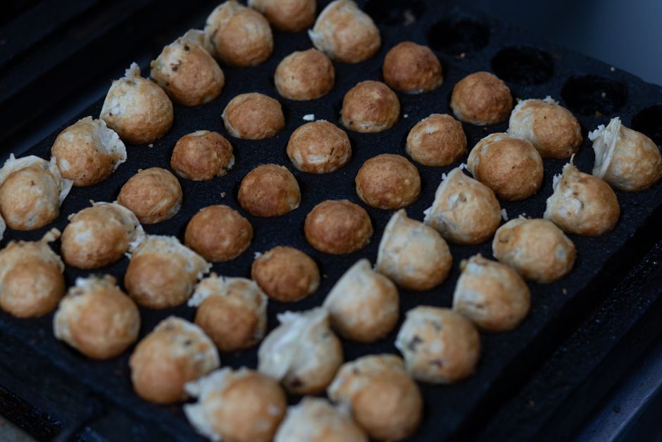 Close-up of Japanese takoyaki balls cooking on a grill, crispy and golden.