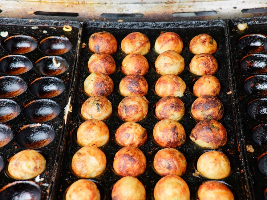 Freshly cooked takoyaki balls on a hot grill, golden brown and crispy.