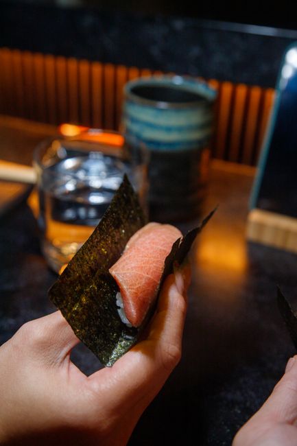 海苔で巻いた寿司を手に持ち店内で食べる様子