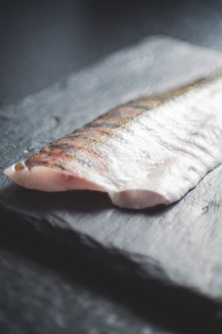 皮目を上にして黒いまな板に置かれた切り身魚のクローズアップ