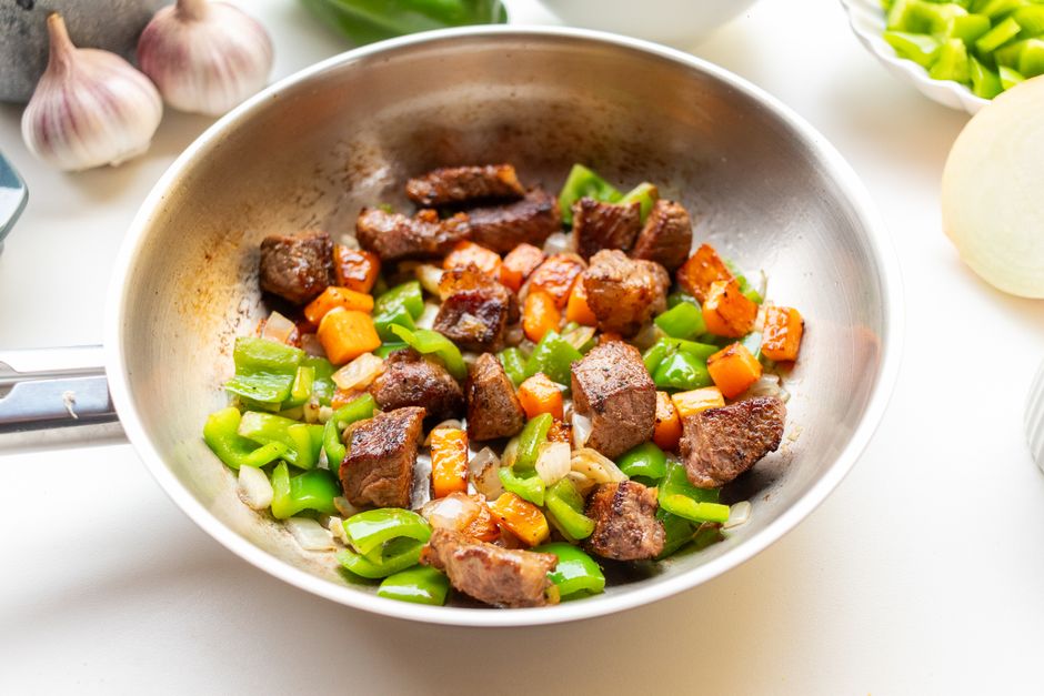牛肉とピーマン、にんじんをフライパンで炒めている様子