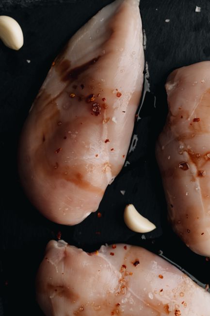 黒い皿に並んだ鶏むね肉、塩とスパイスがまぶされている