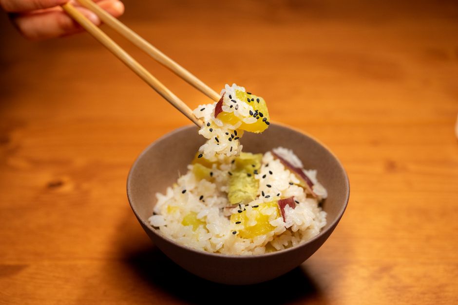 茶碗に入った具だくさんの炊き込みご飯を箸でつまむ様子