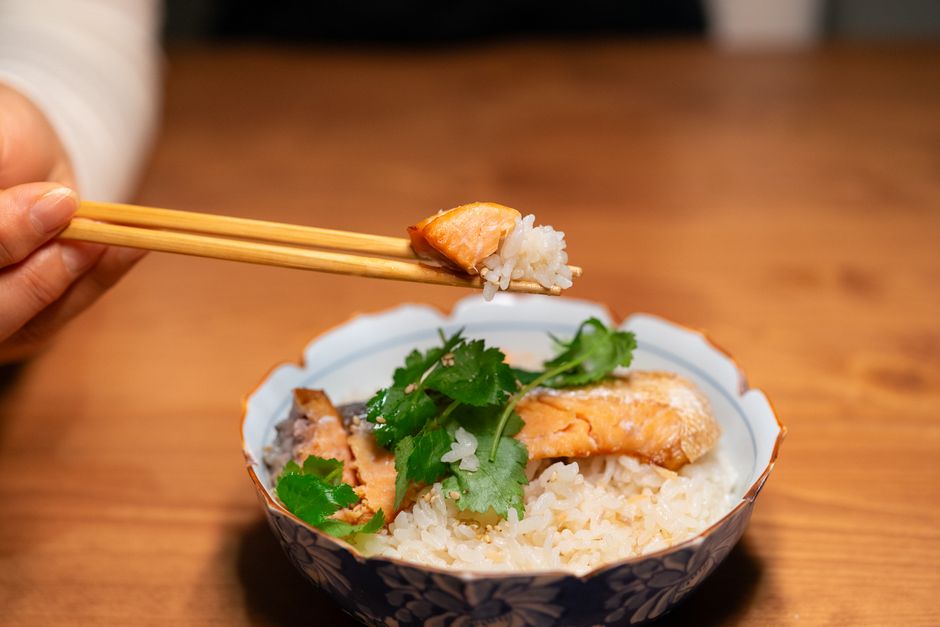 箸でつまむご飯とサーモンの一膳