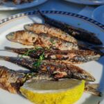 皿に盛られた小型魚の塩焼きとレモン