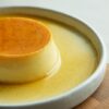 白い皿に盛られたなめらかなカラメルプリン、とろりとしたカラメルソースがかかった様子