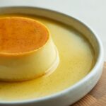 白い皿に盛られたなめらかなカラメルプリン、とろりとしたカラメルソースがかかった様子