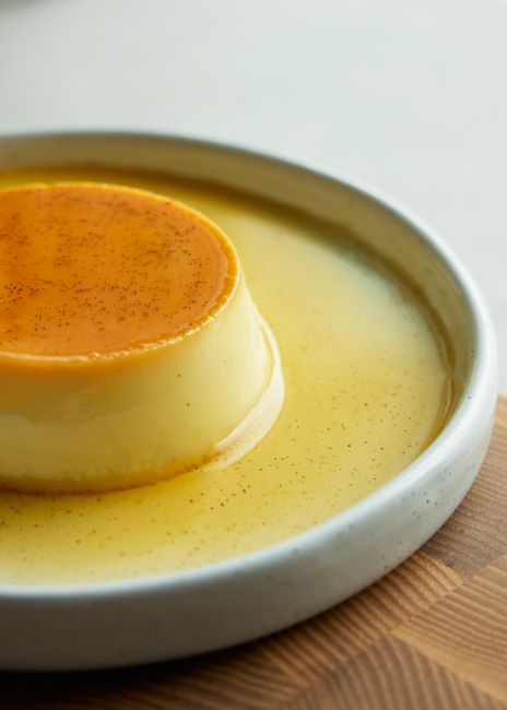 白い皿に盛られたなめらかなカラメルプリン、とろりとしたカラメルソースがかかった様子