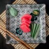赤身のマグロ刺身をわさびや胡瓜と共に和皿に盛り付けた様子