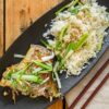白身魚の切り身を長ねぎと香味野菜と一緒に蒸した皿