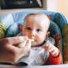 スプーンで離乳食を赤ちゃんに食べさせている手元の様子