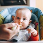スプーンで離乳食を赤ちゃんに食べさせている手元の様子