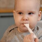 自宅のキッチンでベビーチェアに座り離乳食を食べさせてもらっている赤ちゃん