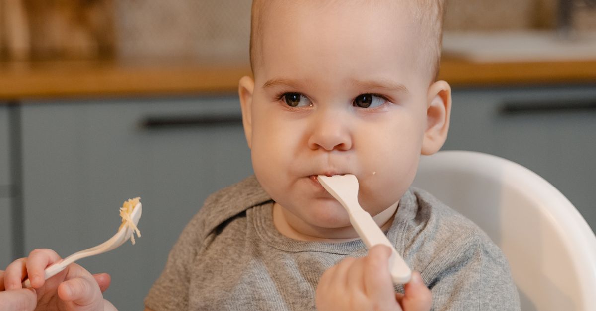 自宅のキッチンでベビーチェアに座り離乳食を食べさせてもらっている赤ちゃん