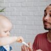 父親がキウイをスプーンで赤ちゃんに食べさせている様子