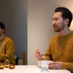 丸いテーブルで一人で食事をする男性、鏡に姿が映っている