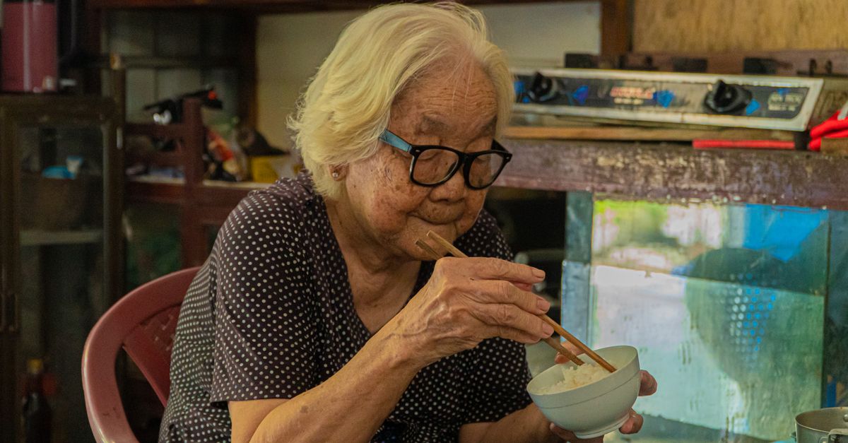 箸でご飯を食べている高齢の女性