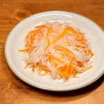 木製の皿に盛られた春雨状の透明な麺と人参の千切り