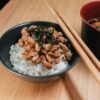 箸を添えた黒い茶碗に盛られたご飯と納豆、味噌汁