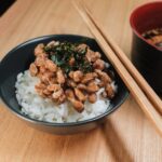 箸を添えた黒い茶碗に盛られたご飯と納豆、味噌汁