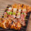 串に刺した色々な部位の焼き鳥を黒い皿に盛り付けた様子