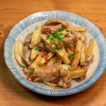 豚肉と根菜(たけのこ・れんこん)を甘辛く炒めた一皿。ごまと青ねぎを散らして盛り付けた様子
