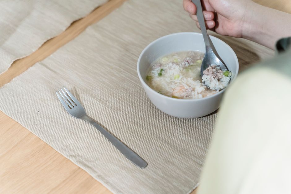 器に入ったおかゆをスプーンですくっている手元