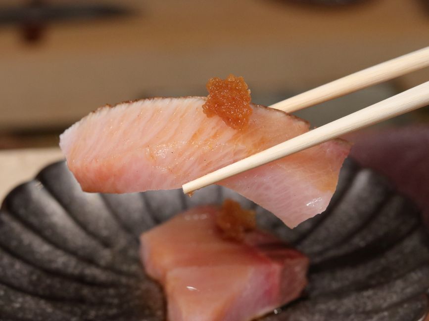 箸でつまむ薬味付きの刺身と魚卵