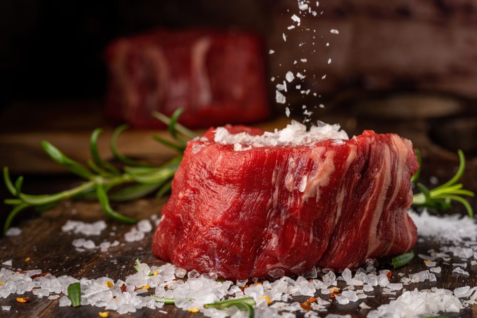 岩塩をふった生の牛肉の塊とローズマリー