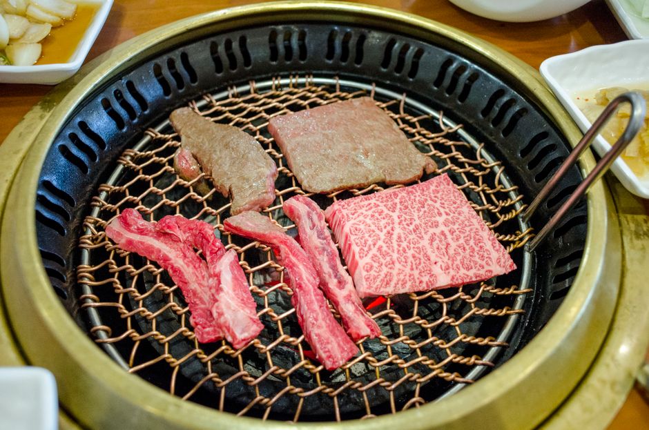 焼肉用の網にのせた牛肉とカルビ