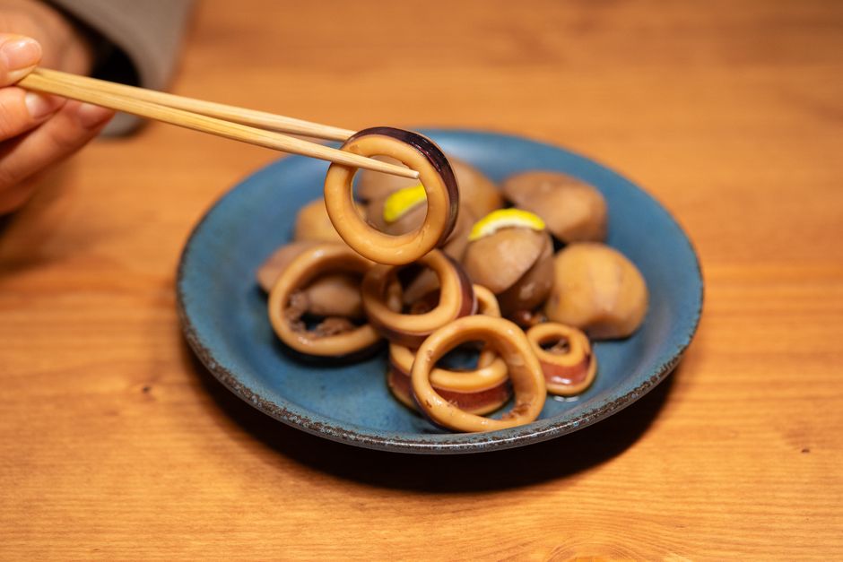 箸でつまんだ輪切りのいかの煮物