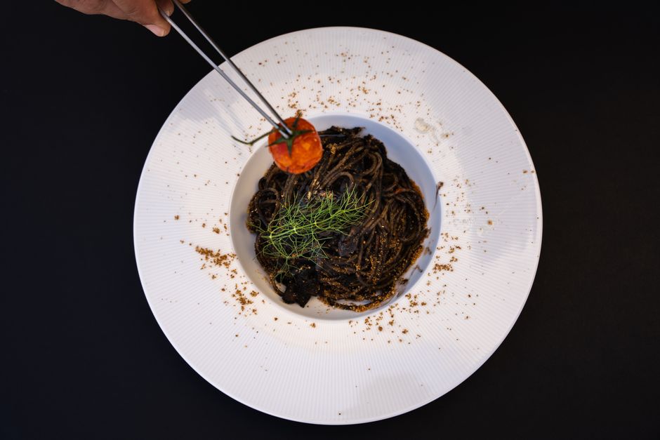 白いリム皿に盛りつけたいか墨のパスタ