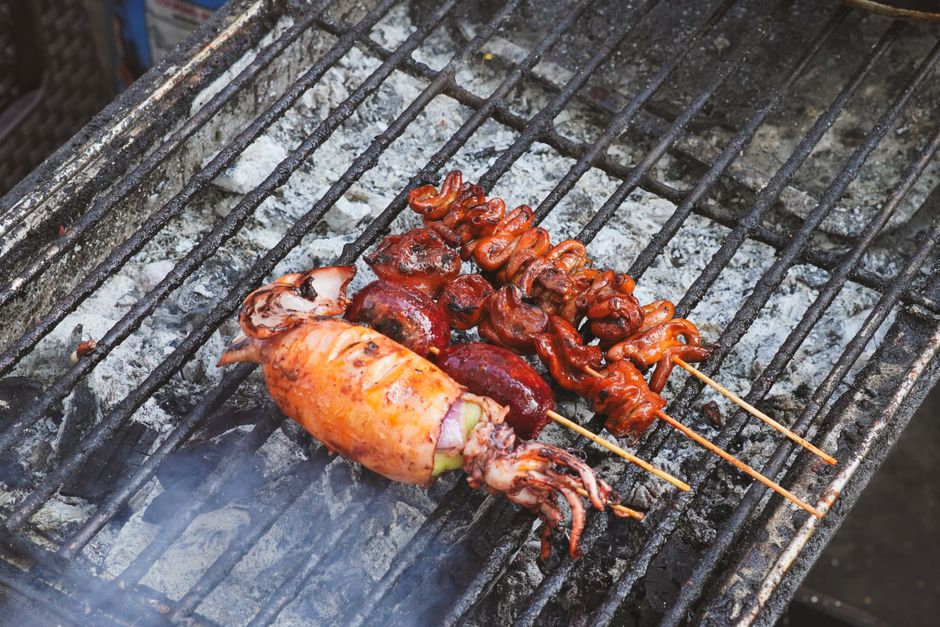 炭火の網で焼いているいかの串焼き