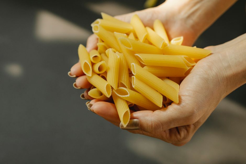 両手いっぱいにペンネパスタをすくって量を見せている様子