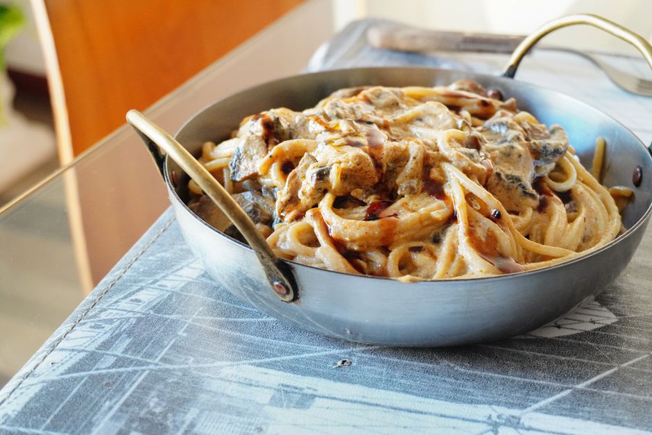 フライパンでクリームソースのパスタを仕上げている様子
