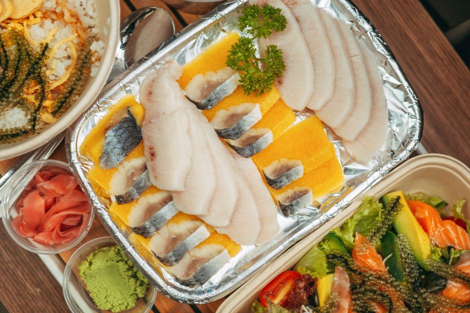 アルミトレーに並べた白身魚の刺身と、ガリ・わさびを添えた盛り付け