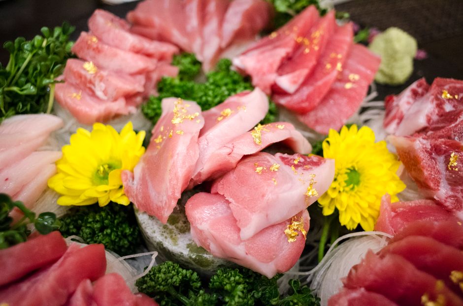 金箔をあしらった魚の刺身と黄色い菊の花で彩った豪華な盛り合わせ