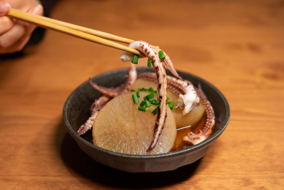 いかの足と大根を煮た一品を箸でつまむ様子