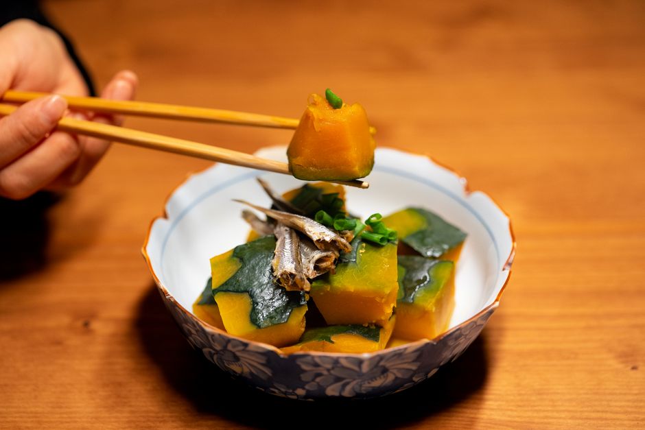 かぼちゃと小魚を炊き合わせた煮物を箸でつまむ様子